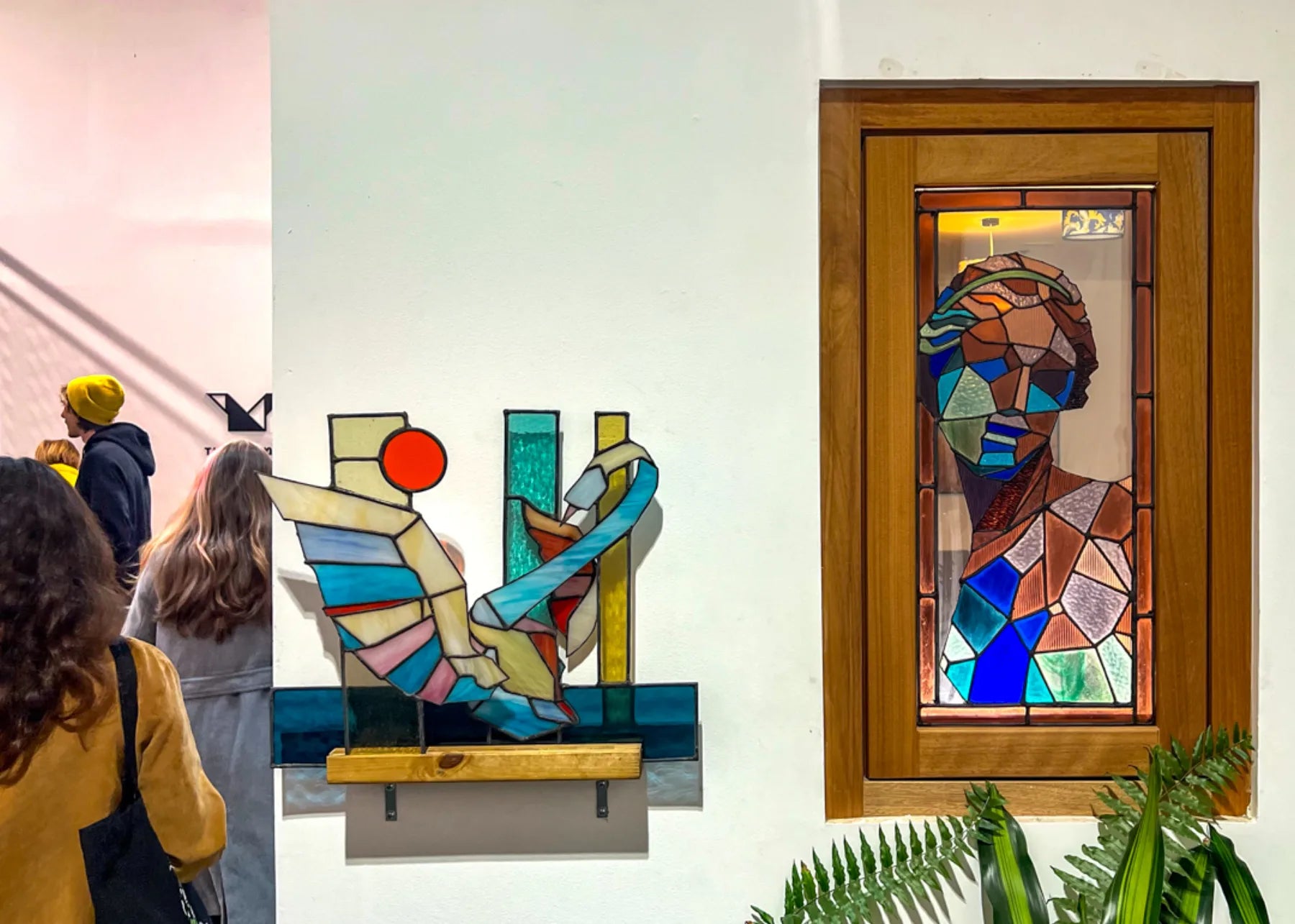 Visitors viewing stained-glass figures in an exhibition
