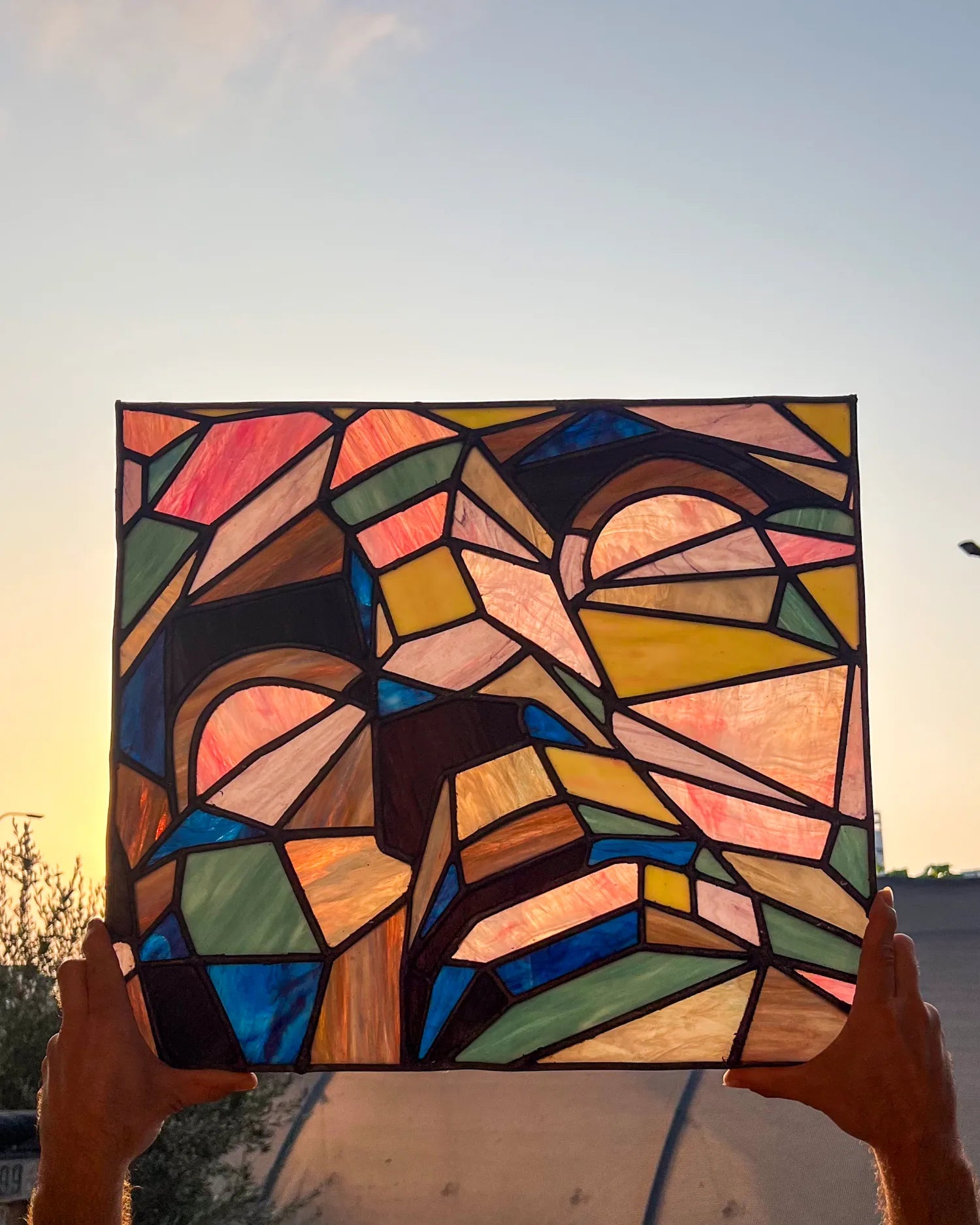 A faceted stained-glass face held up to warm daylight