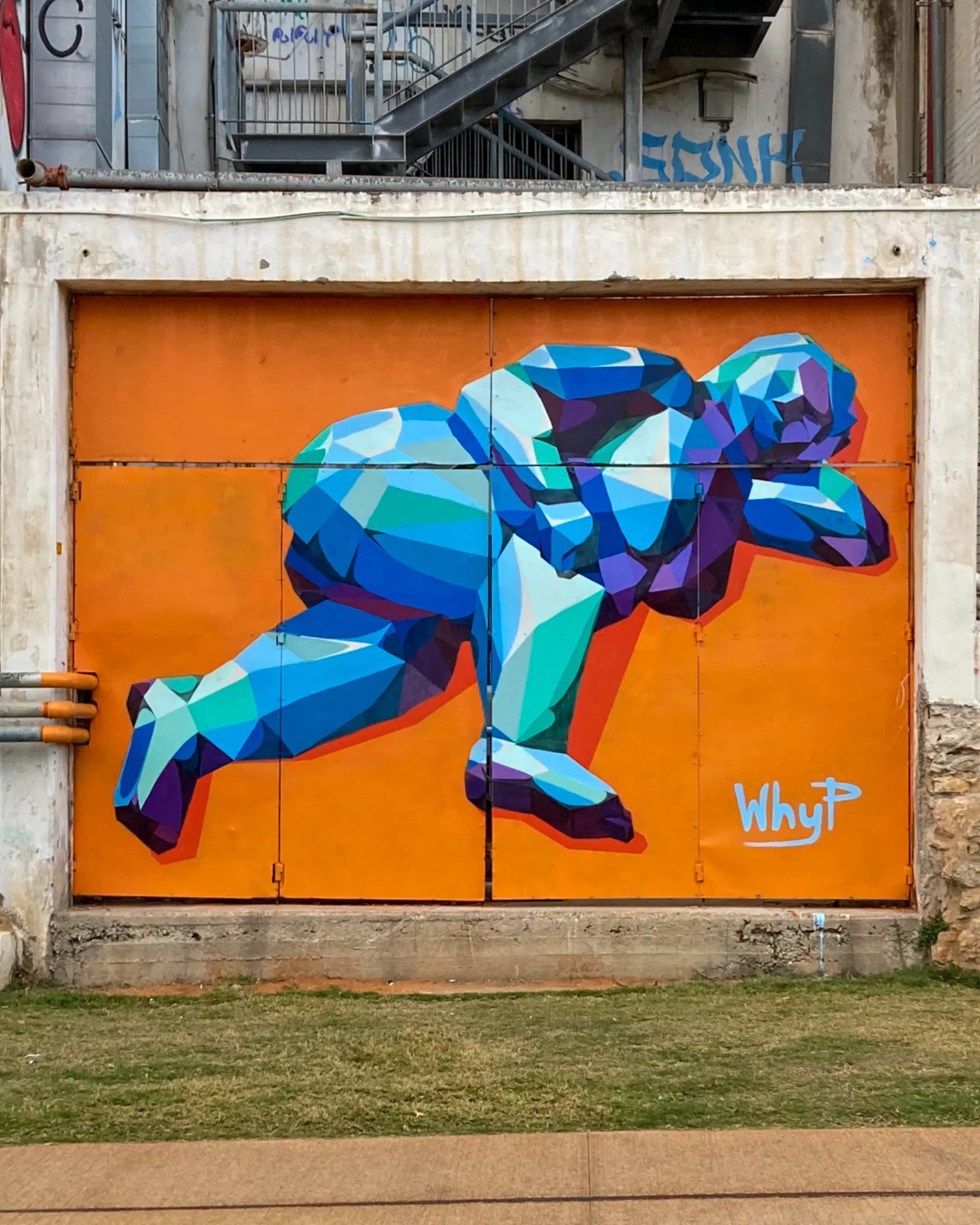 Blue faceted diver painted across an orange urban wall